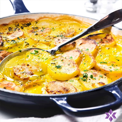 Gouden aardappelschijfjes gegaard met saffraan in ovenschaal